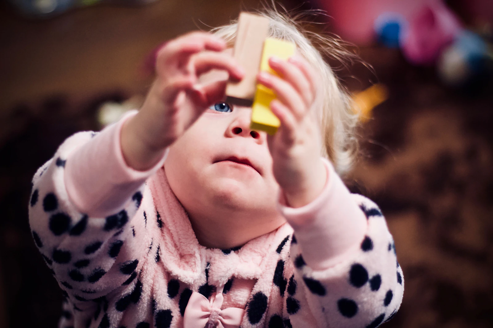 A toddler sitting on the floor holding two wooden blocks