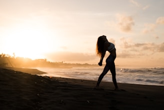 A serene seaside scene with a person practicing pilates at sunrise