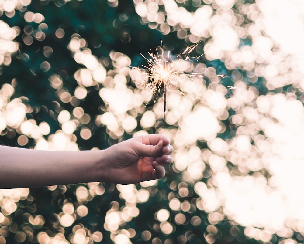 Fotografia bokeh di una persona che tiene in mano la scintilla