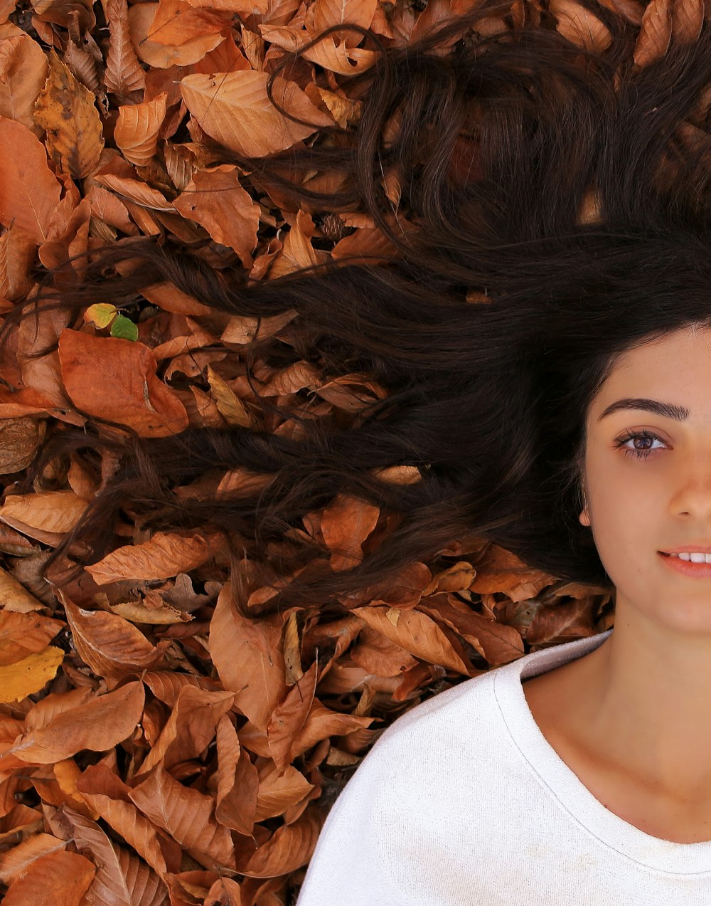 woman lying on ground with brown leaves