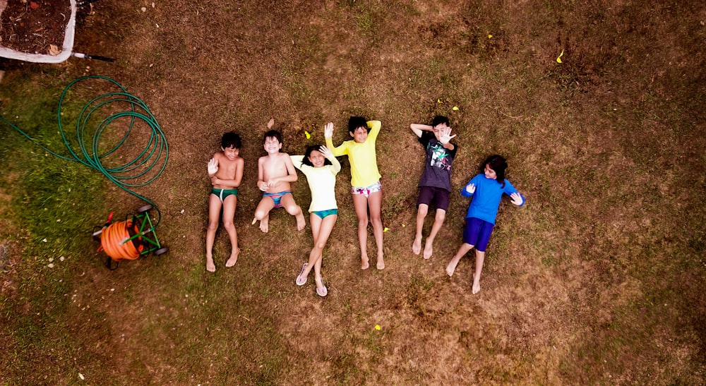 grupo de crianças ao lado do carretel da mangueira do jardim