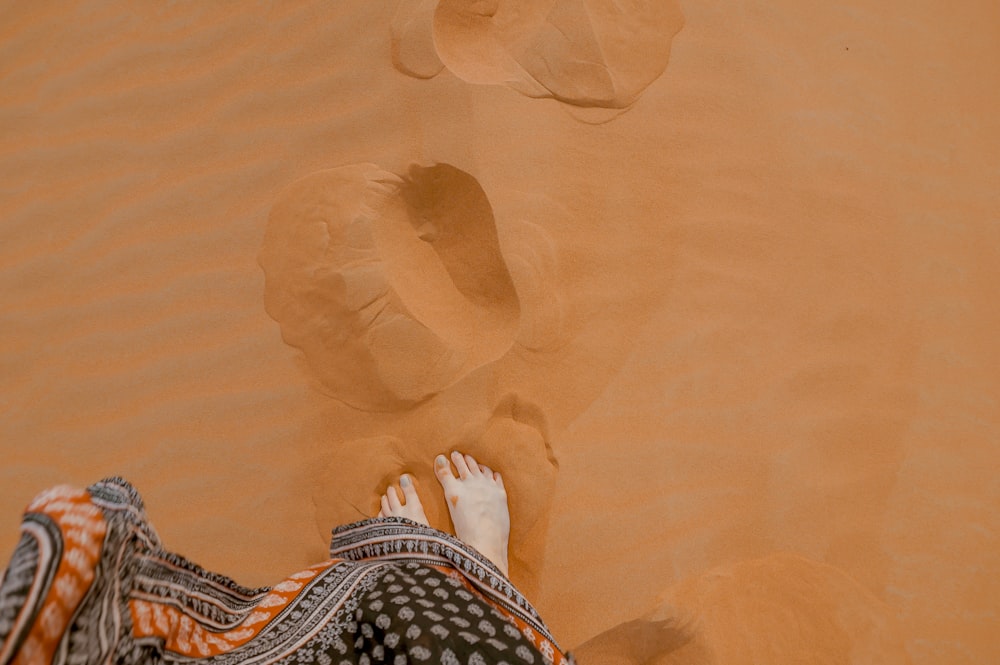 Foto einer Person, die auf orangefarbenem Sand steht