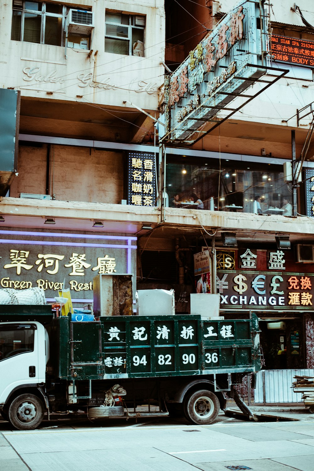 green and white dump truck parking beside building