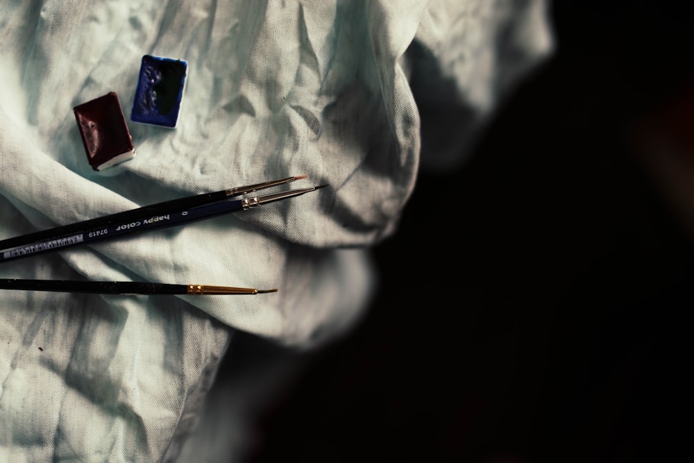 three paint brush on white textile