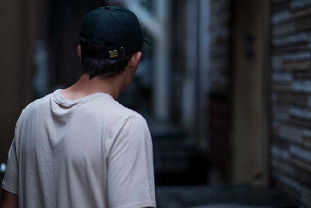 photo of man wearing white crew-neck T-shirt and black cap