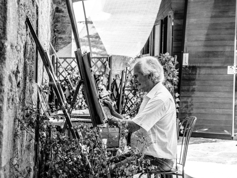 Foto in scala di grigi di un uomo seduto mentre dipinge