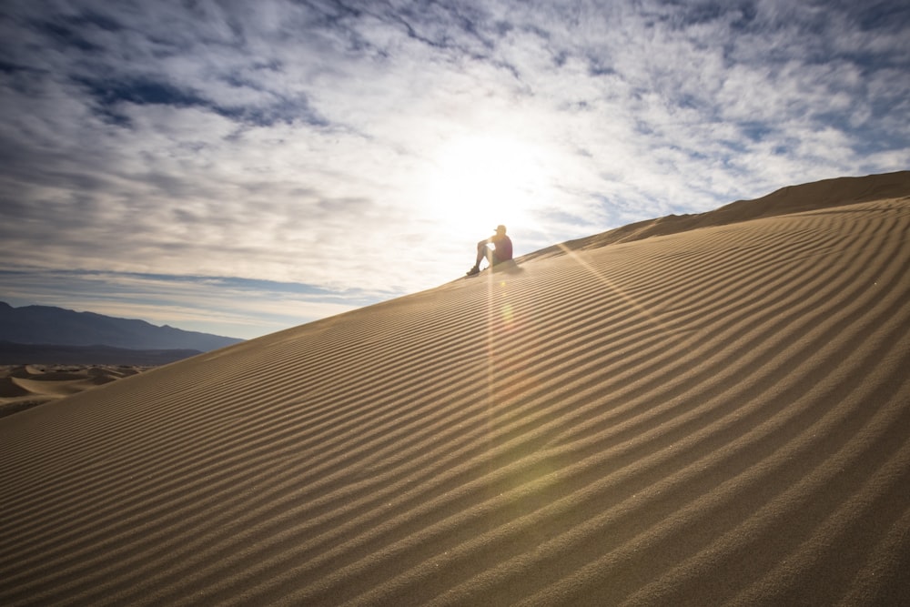 Persona che si siede sul deserto durante il giorno