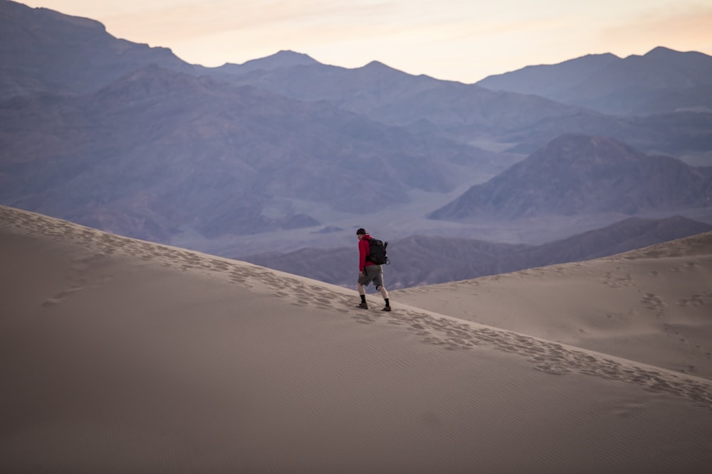 person in red hoodie walking on desert