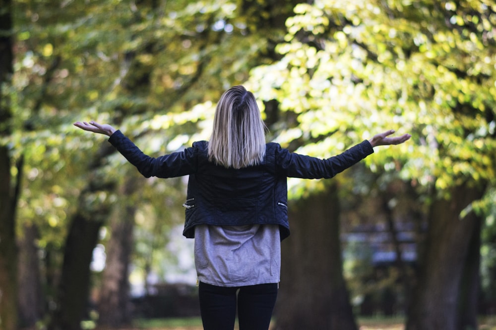 Frau in schwarzem langärmeligem Top vor grün belaubtem Baum