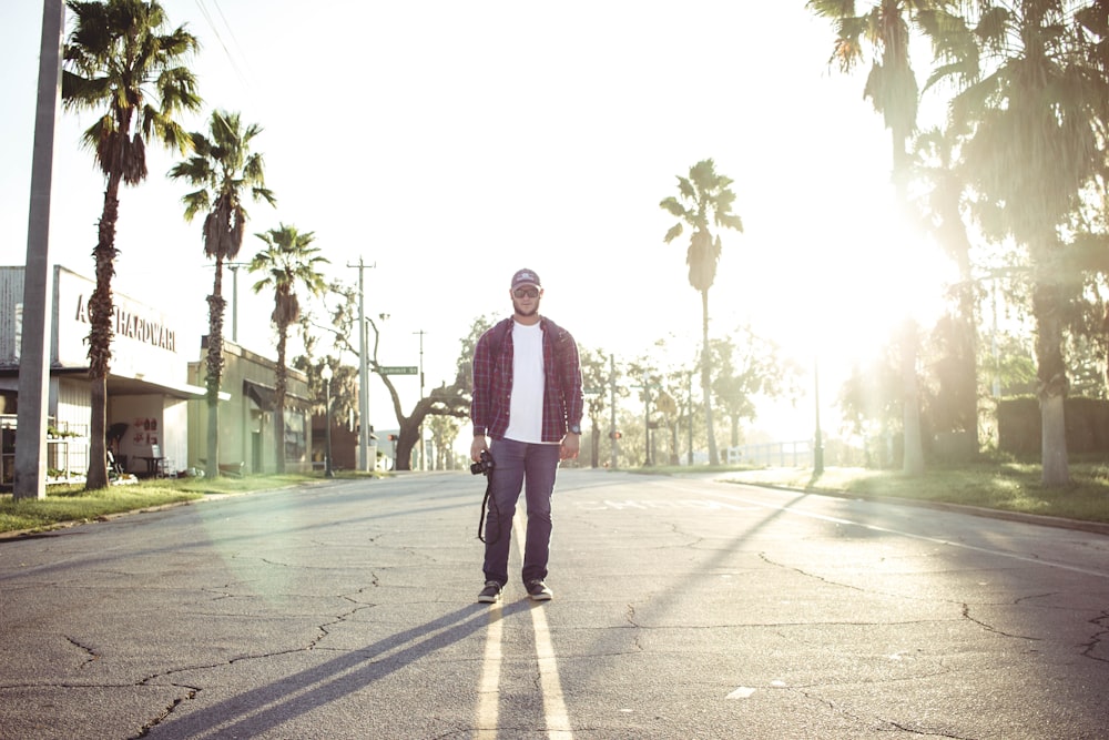 man holding black DSLR camera standing on road during daytime