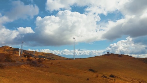 Wind turbines turning gracefully on a sunny day over rolling hills.