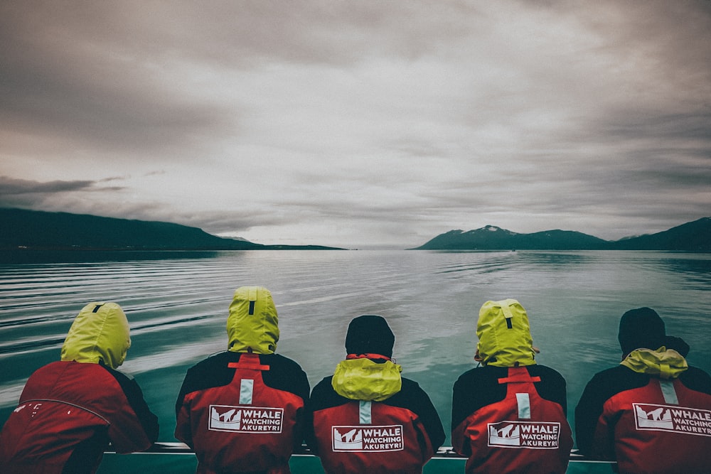 people near body of calm water under gray sky during daytime