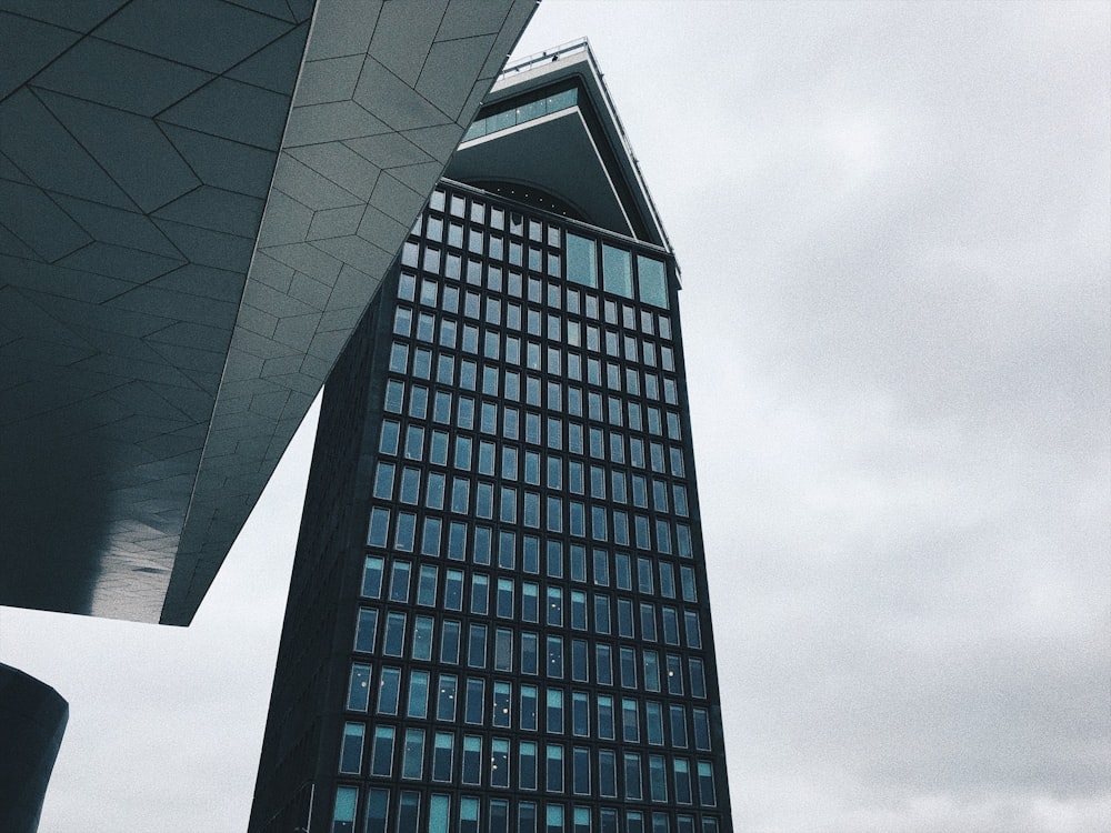 Photo d’un bâtiment en béton noir avec du verre sous un ciel nuageux