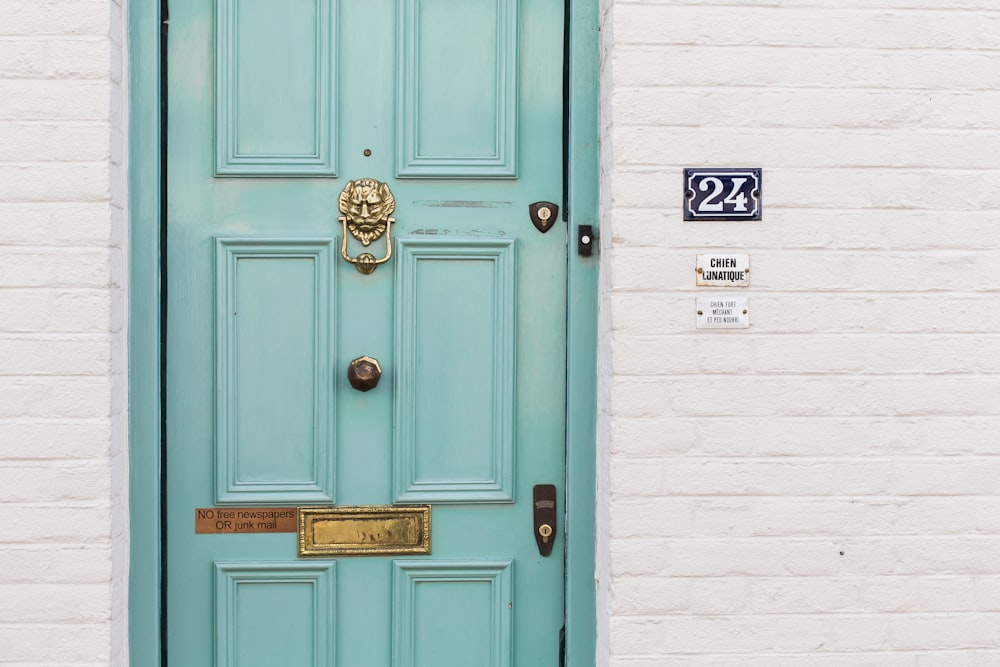 teal wooden door beside white concrete wall