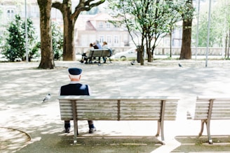 person sitting on beige street bench near trees