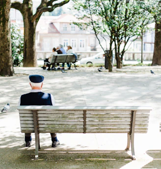 person sitting on beige street bench near trees