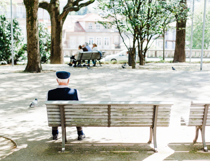 person sitting on beige street bench near trees