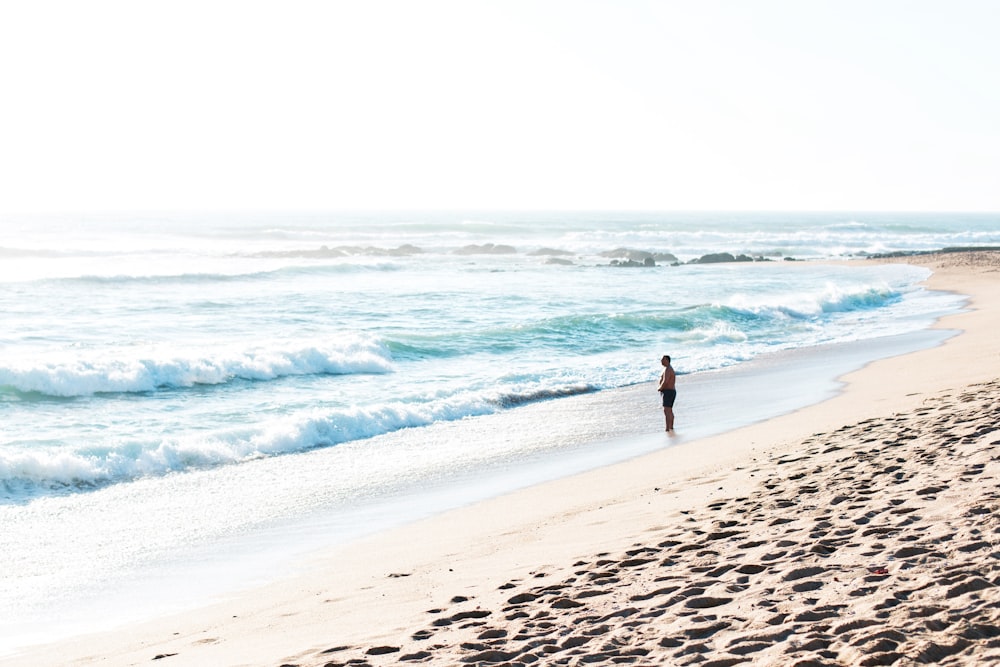 homme debout près de la vague de mer pendant la journée