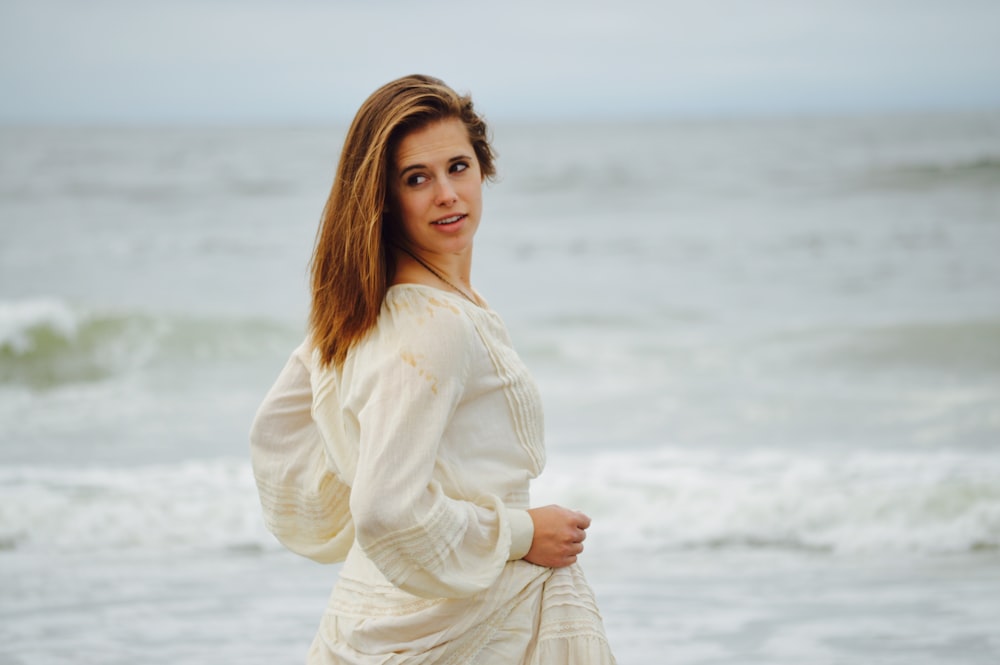 focus photo of woman in white long-sleeved dress on seashore