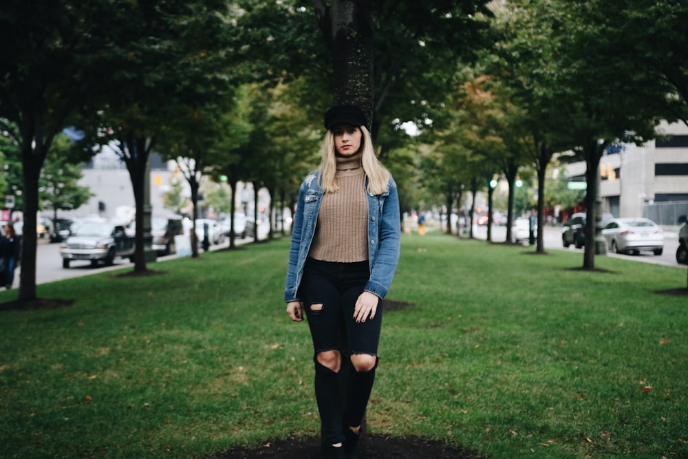 woman standing on green grass in between of green leafed trees