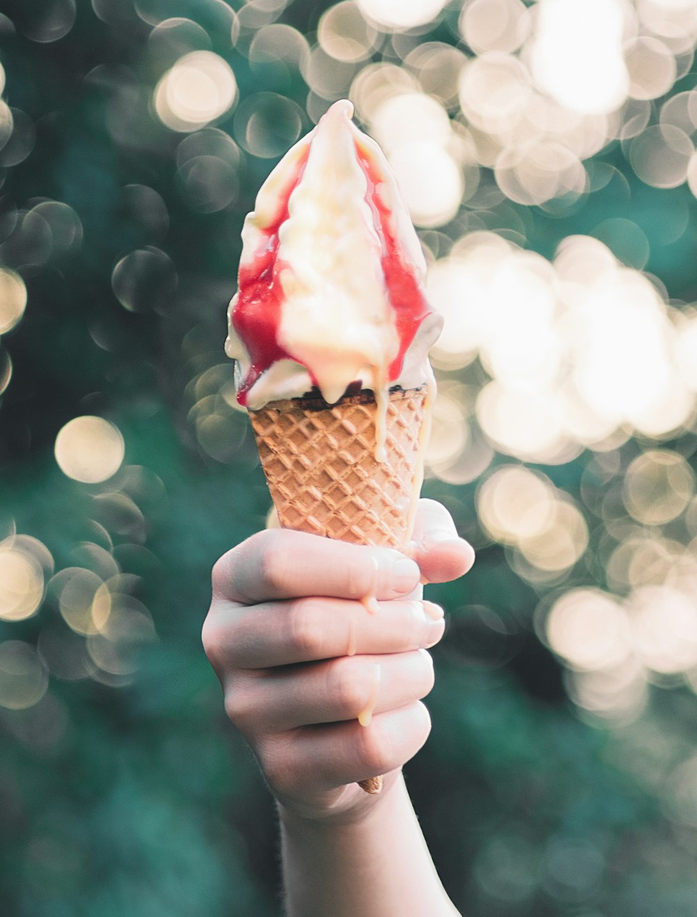 personne tenant un cornet de crème glacée brune avec de la crème glacée aromatisée à la fraise