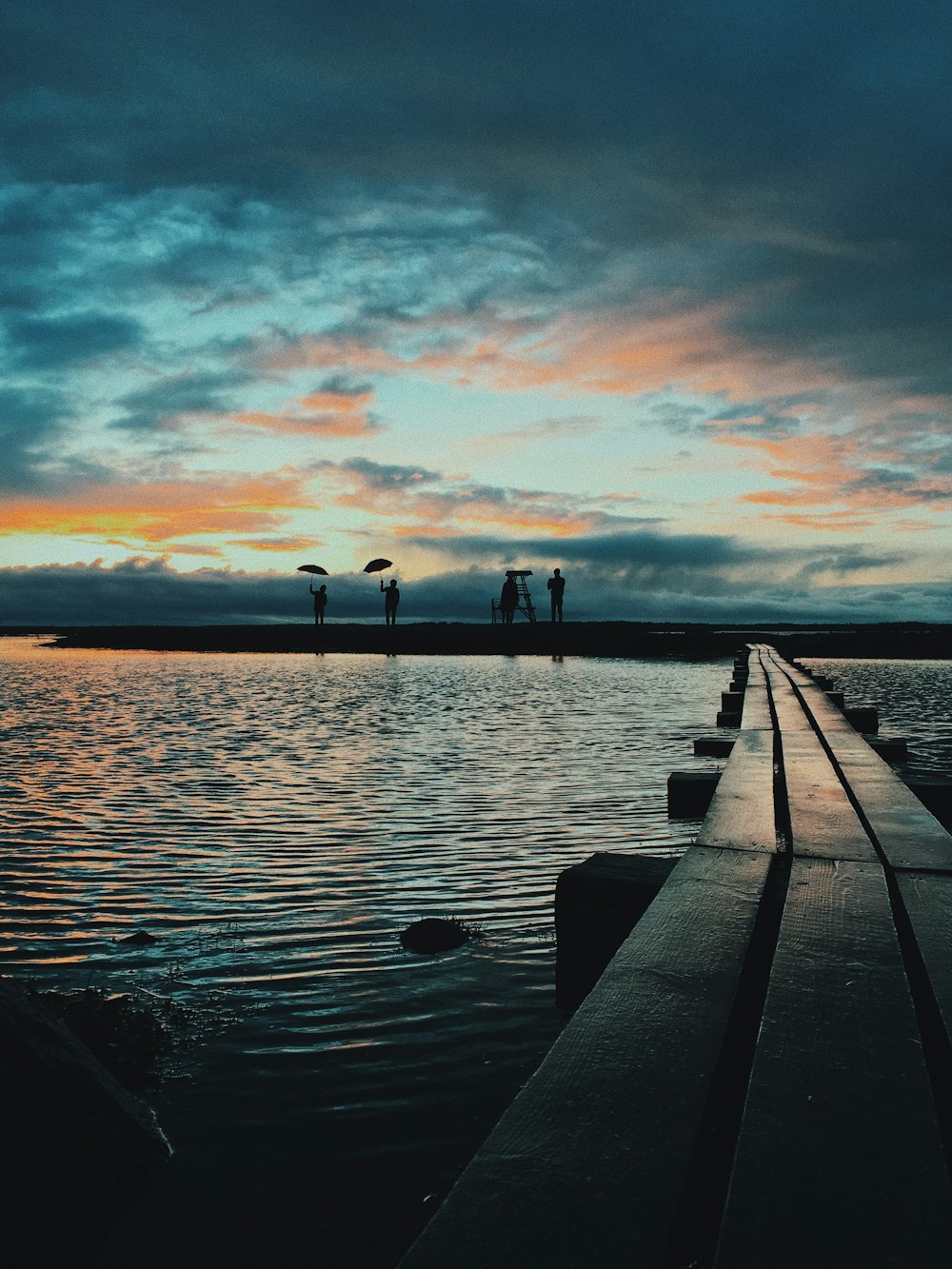 silhouette of four persons on dock