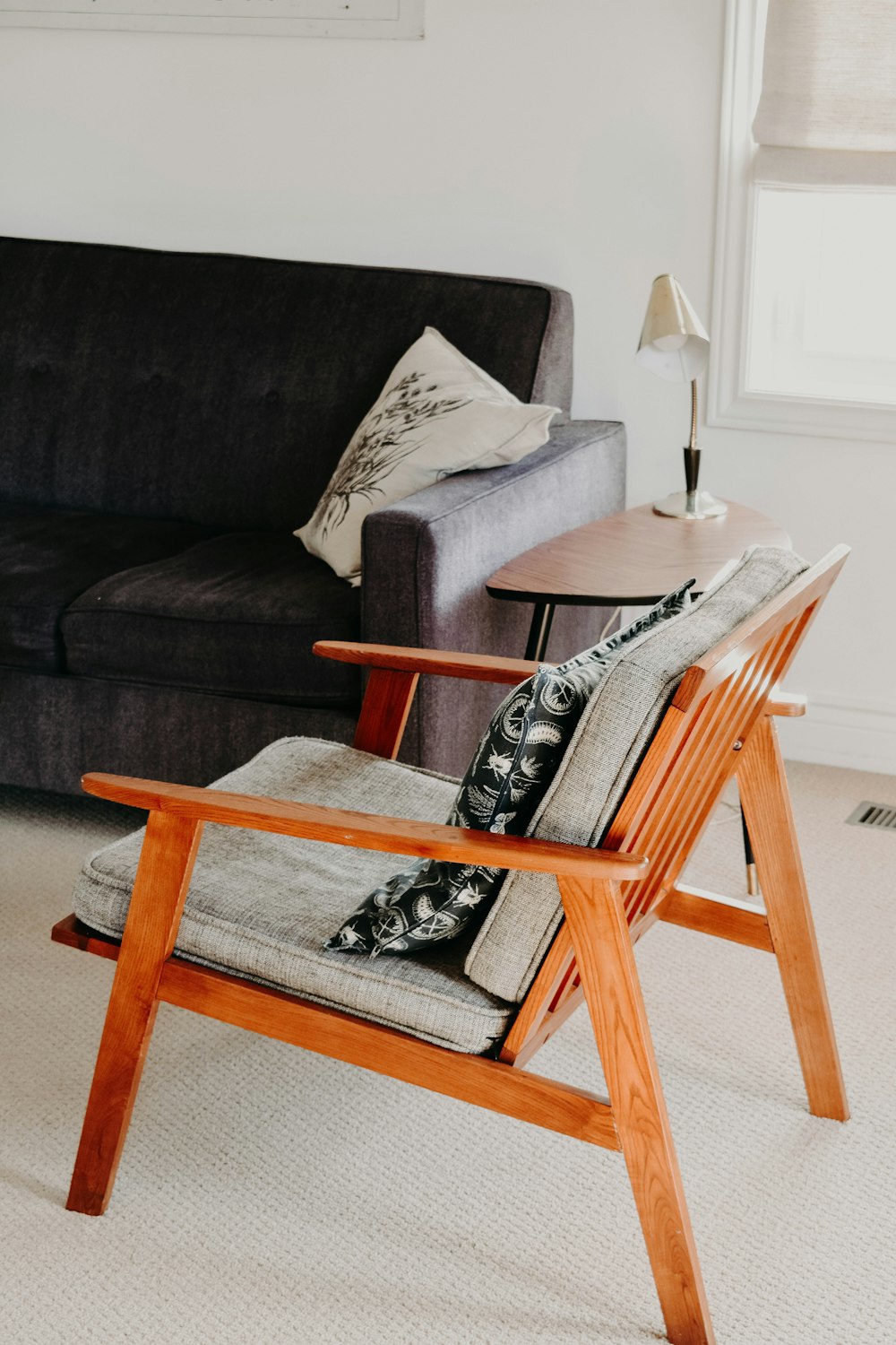 grauer Sessel mit braunem Holzgestell auf beigefarbenem Teppich