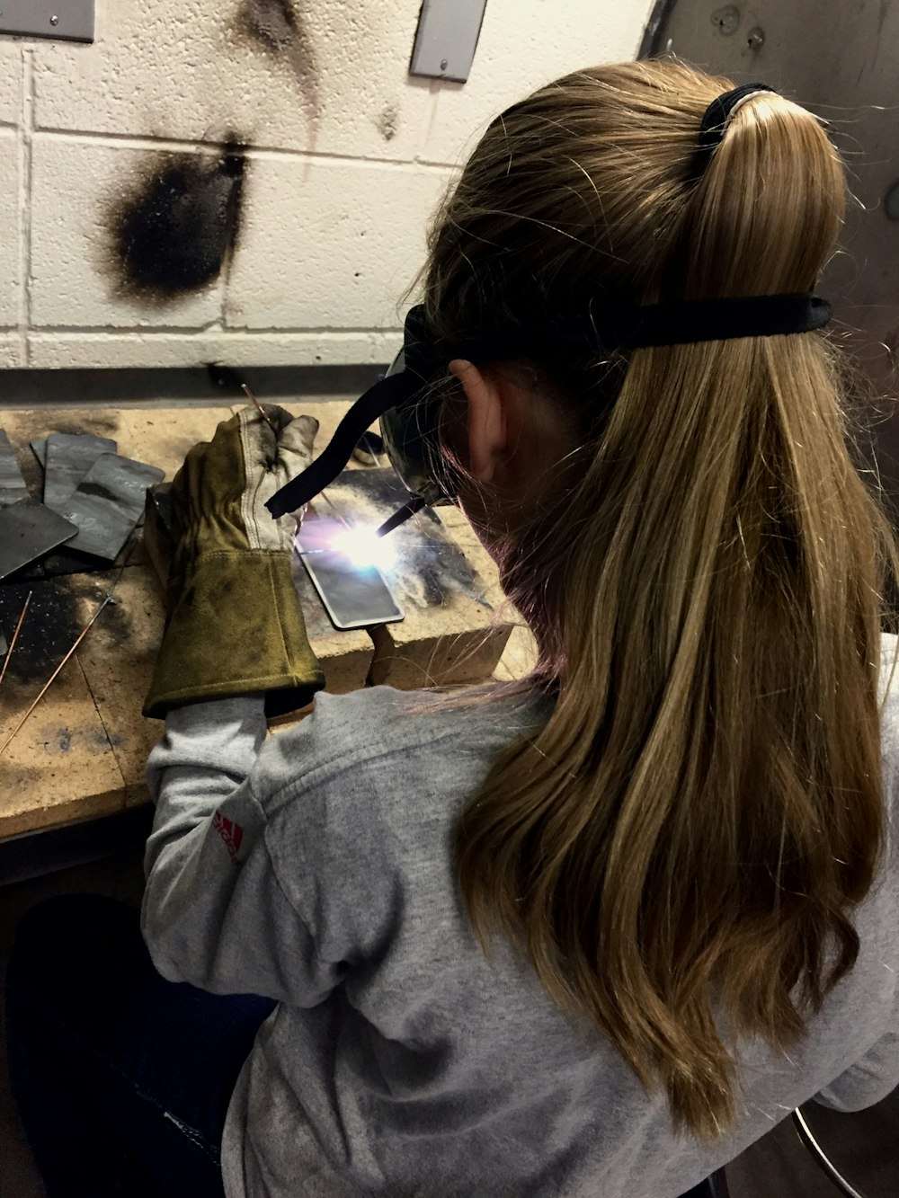 woman welding grey metal plate