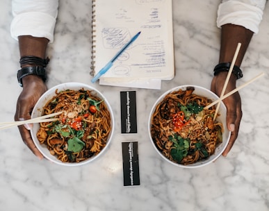 person holding two bowls of cooked foods