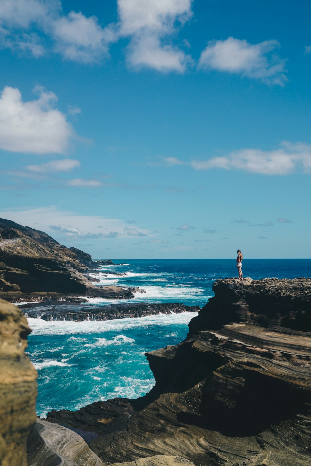 person standing on rock mountain beside body of water