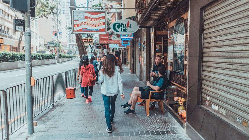 woman walking on sidewalk near rail and stores