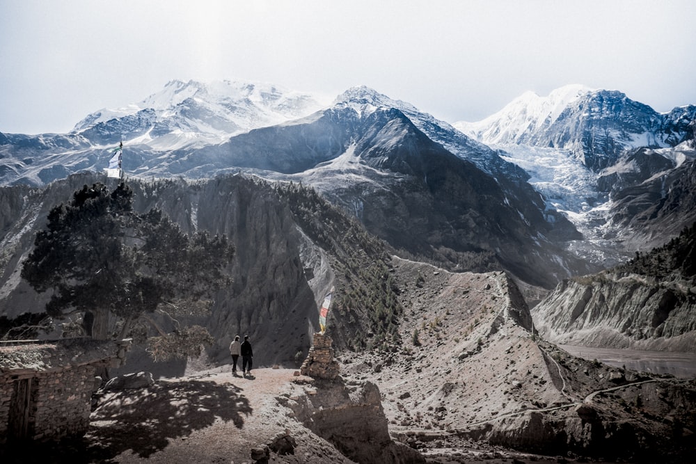 two people standing on cliff with mountains at daytime