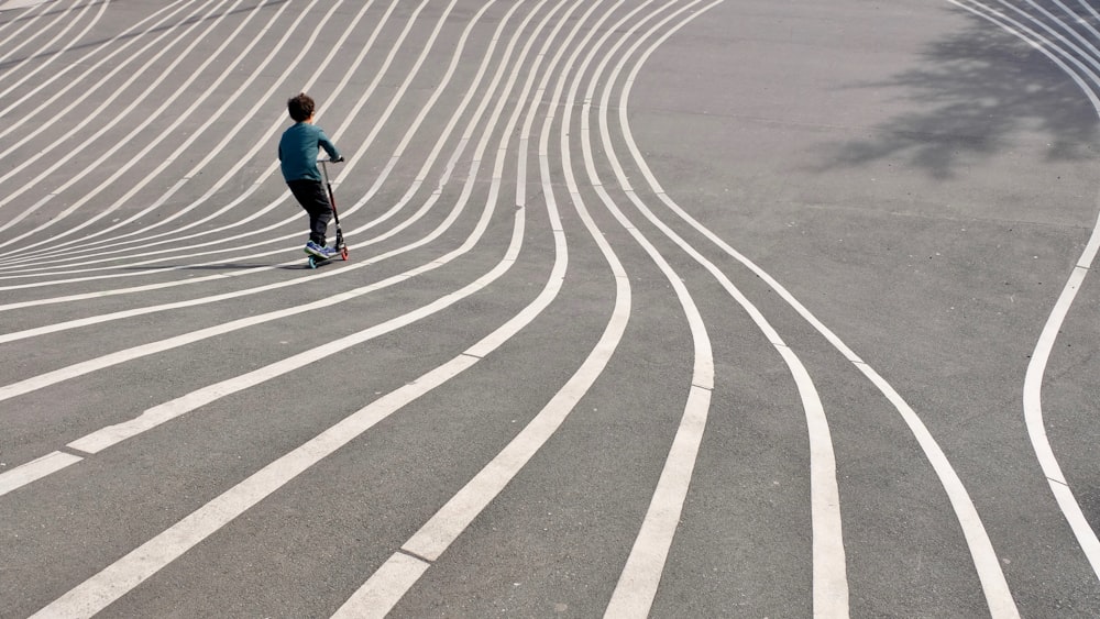 Junge spielt Tretroller auf grauem Betonpflaster