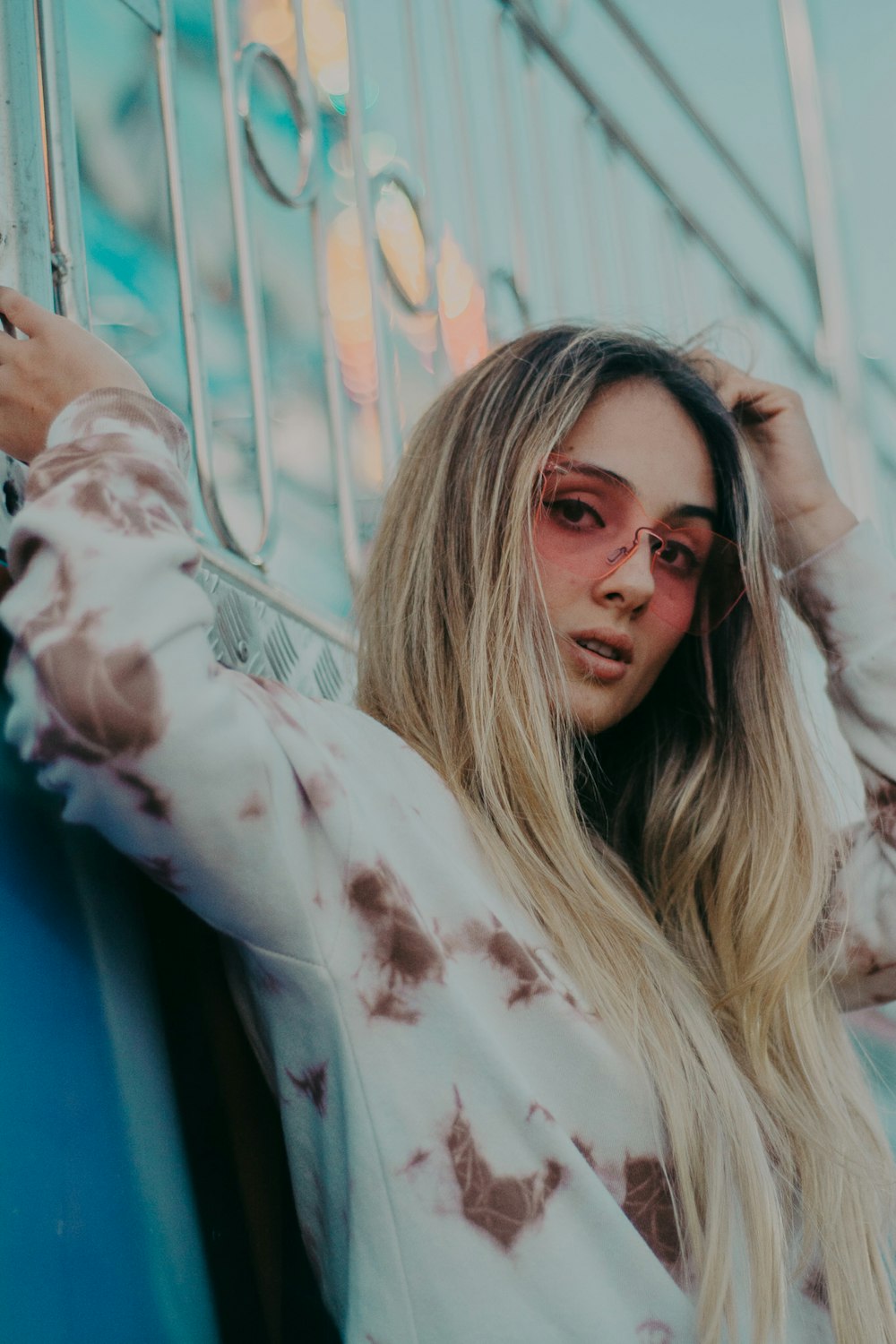 Mujer vestida con camisa de manga larga blanca y marrón apoyada en barandillas de metal gris