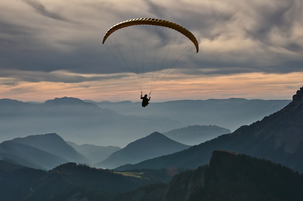 person doing paragliding under cloudy sky