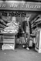 A senior couple at a local market, choosing fresh fruits with guidance from a supportive aide.