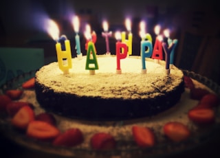 round Happy Birthday cake with lighted candles