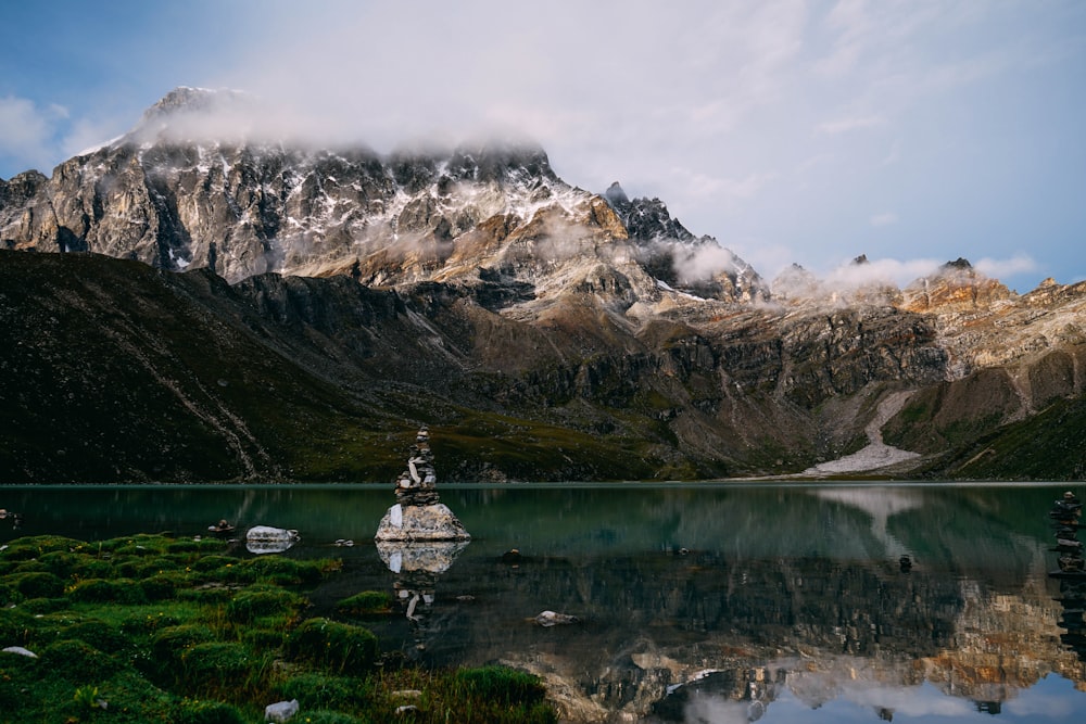 white and gray stone cairn in the middle of body of water near alp mountains