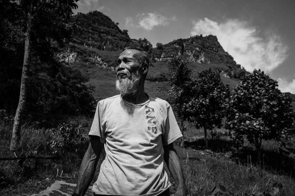 grayscale photography of man standing near trees