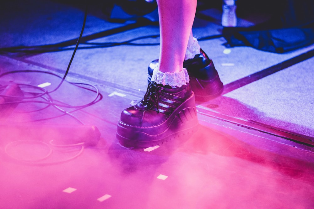 person wearing pair of black leather dress shoes on gray surface