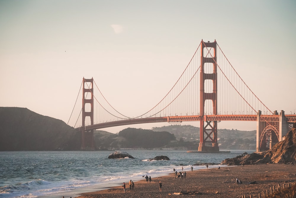 people walking near red bridge on body of water during daytime photo