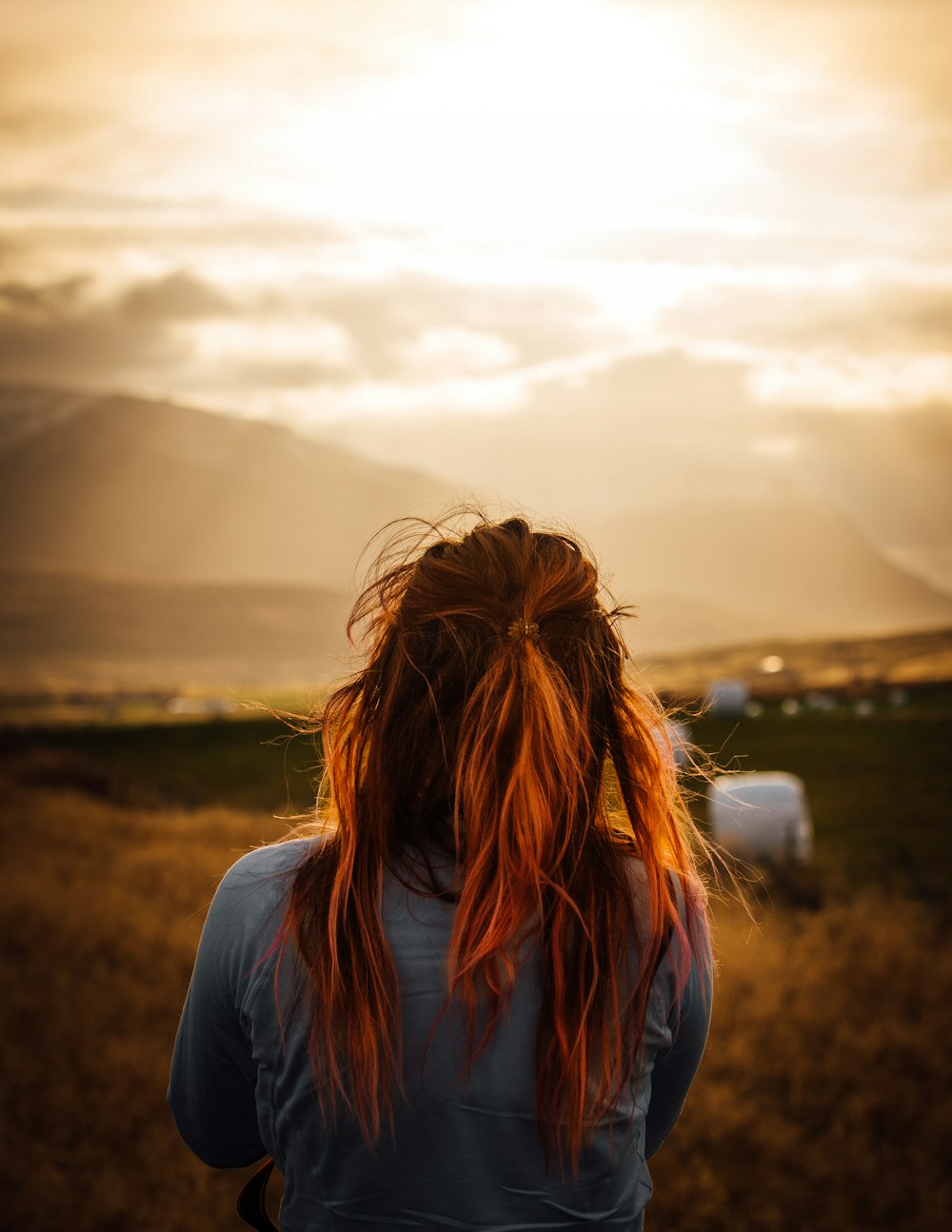 back view of woman facing grass fields