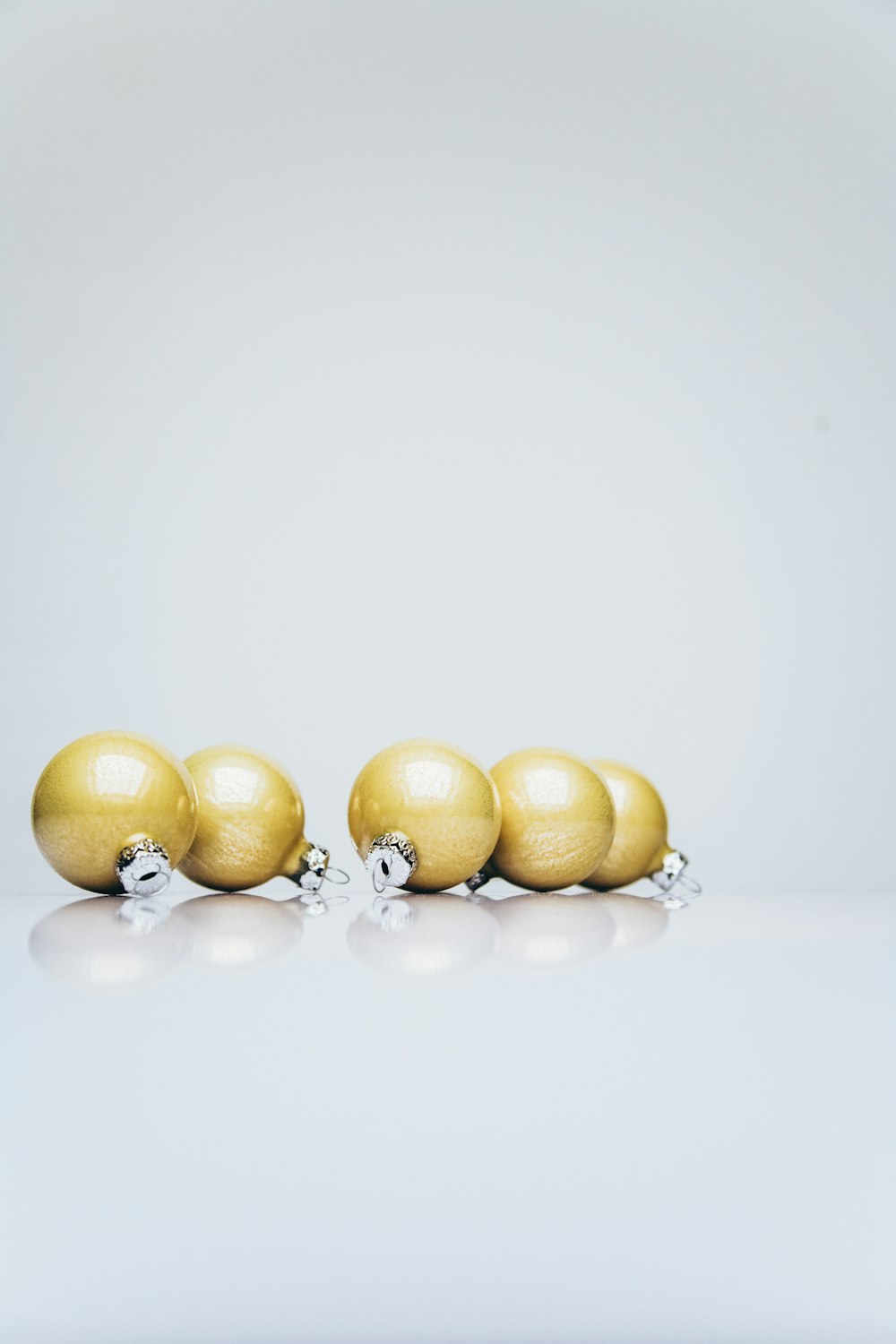 six gold Christmas baubles on white wooden surface