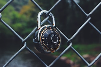 black and gray code padlock anchored on chain-link fence selective focus photo