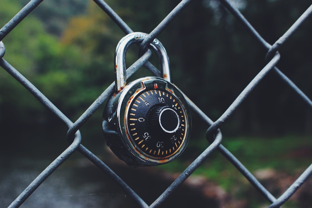 Cadenas code noir et gris ancré sur une clôture à mailles losangées mise au point sélective Photo