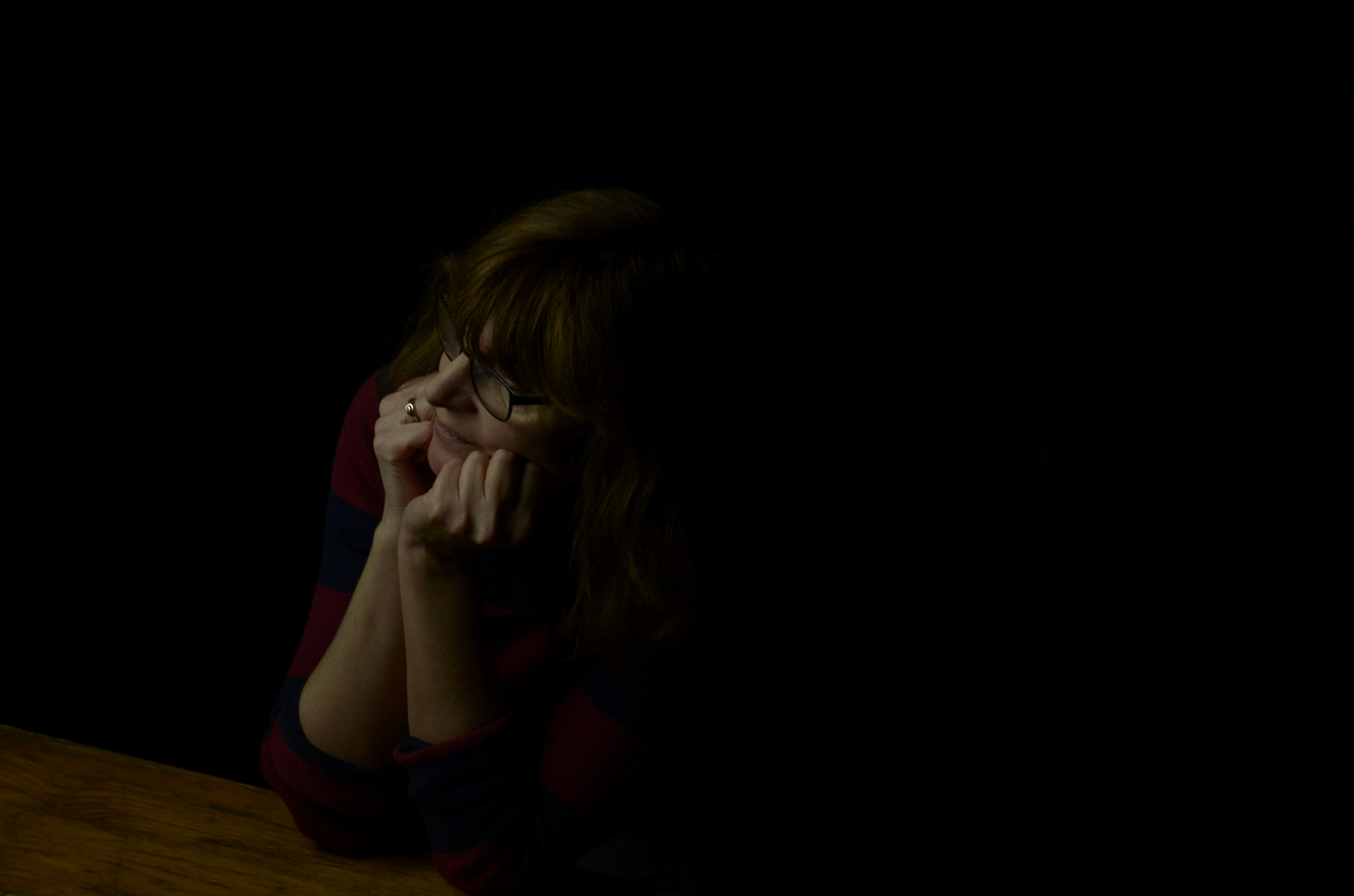 A close-up shot of a distraught but determined middle-aged woman, possibly wiping a tear, with a distant, resolute look in her eyes. The background is slightly blurred, suggesting a home or a somber setting.