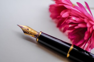 black and gold-colored fountain pen beside flower