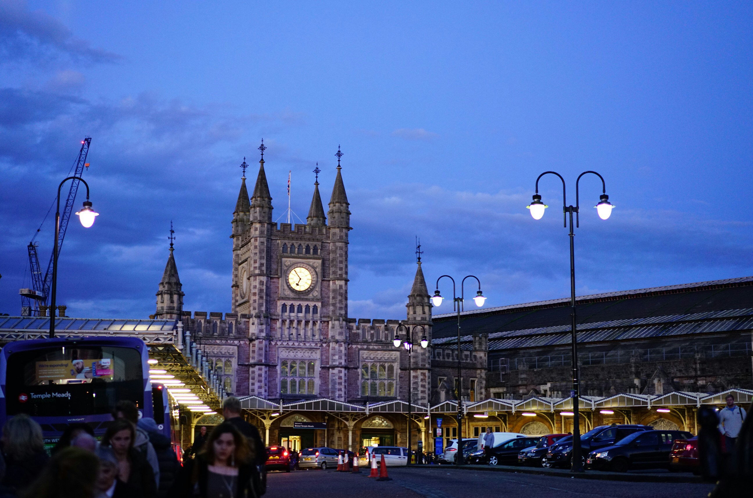 Cinematic view of luxury heritage steam train departing grand Victorian station at dusk with golden platform lights and atmospheric steam