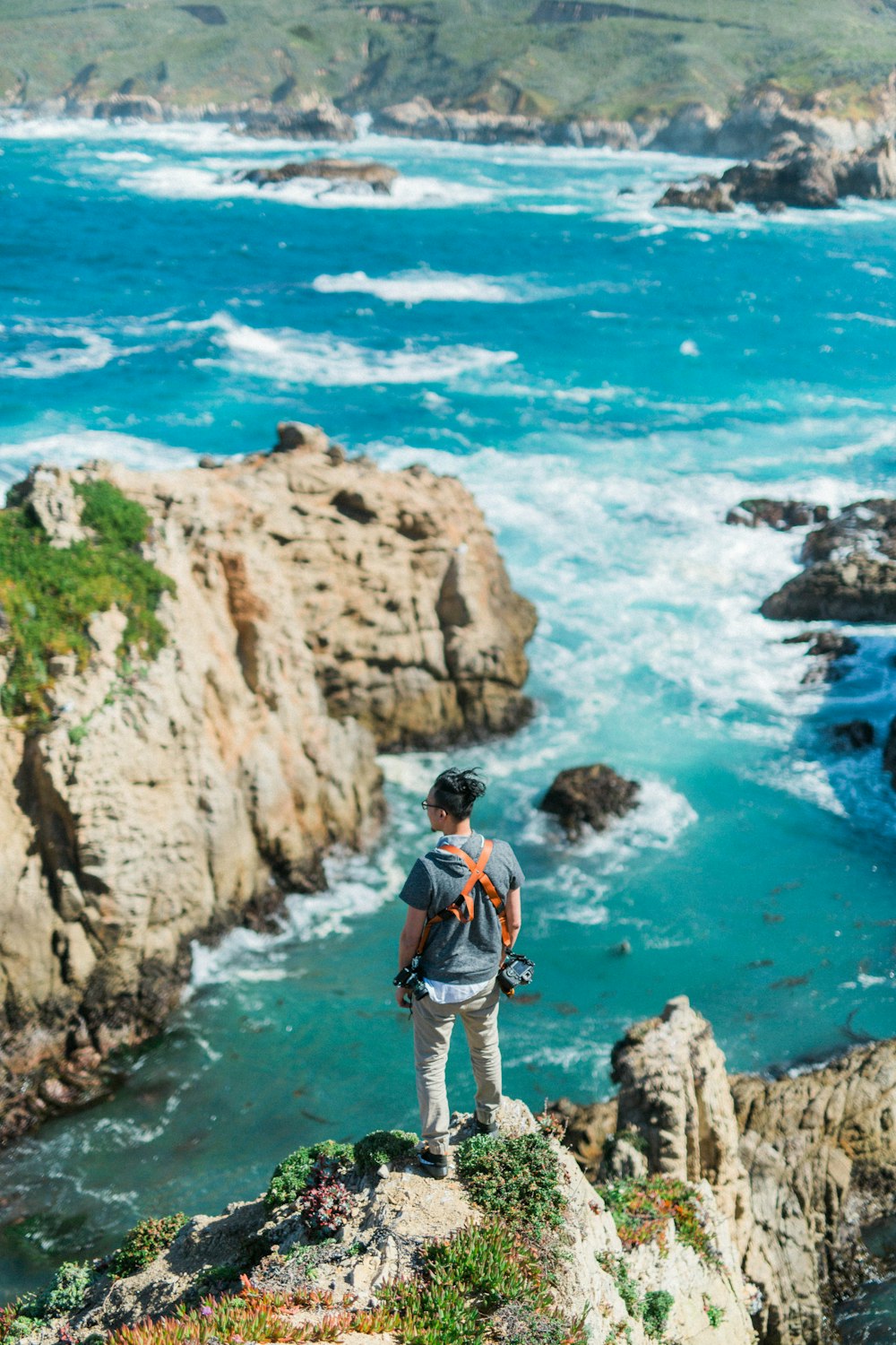 man on cliff near body of water