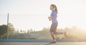 woman jogging near wire fence